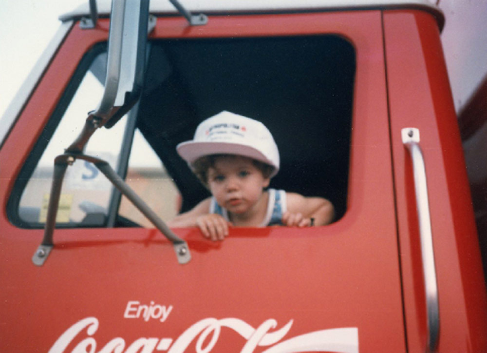 A young, precocious Chris Cottrell hanging out of a Coca-Cola pickup truck